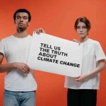 Couple holding sign asking for the truth about climate change